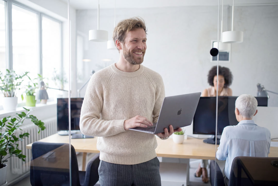 man in office with laptop in hand